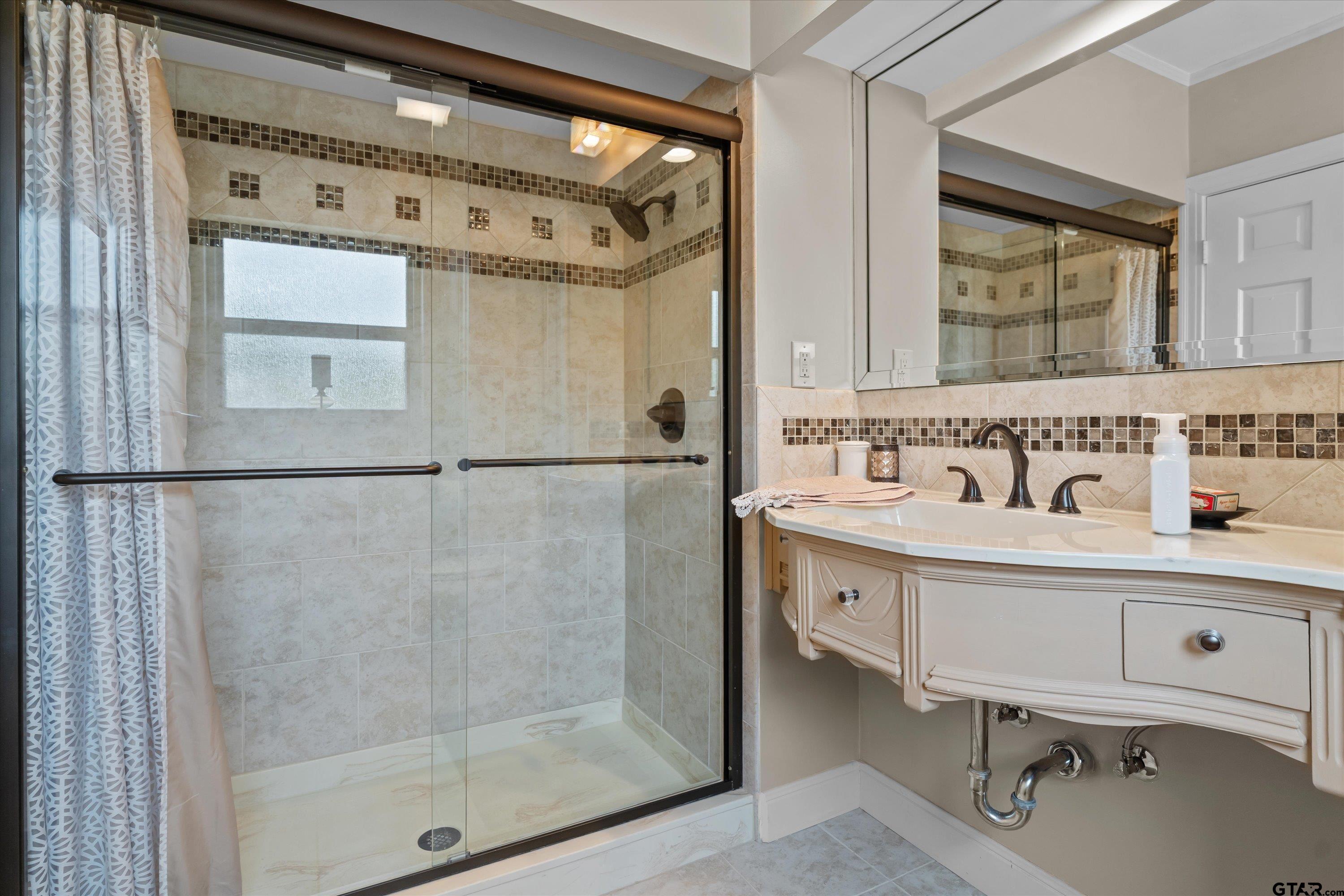 121 Fair Lane Tyler, TX 75701 - Photo 31 of 46 a bathroom with a double vanity sink a mirror and a shower