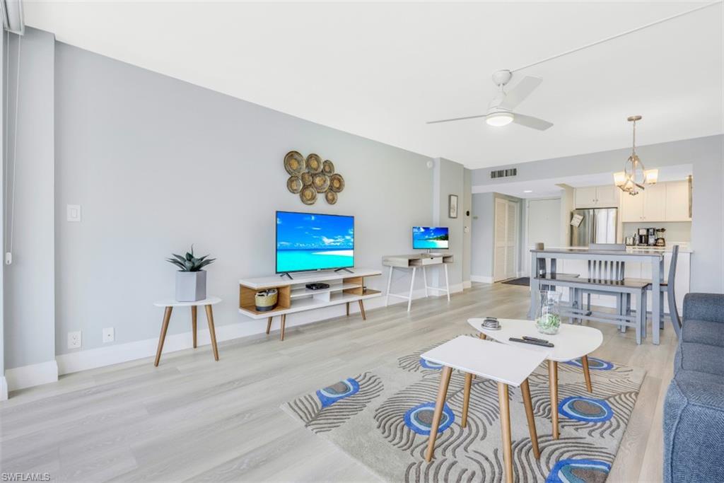 5 Bluebill Avenue, Unit 210 Naples, FL 34108 - Photo 5 of 26 a living room with furniture and a dining table with wooden floor