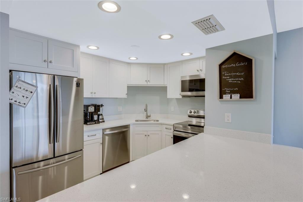 5 Bluebill Avenue, Unit 210 Naples, FL 34108 - Photo 7 of 26 a kitchen with a refrigerator a stove top oven a sink and dishwasher