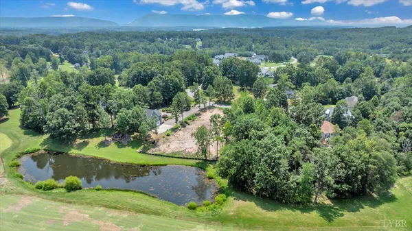 an aerial view of a houses with a yard and lake
