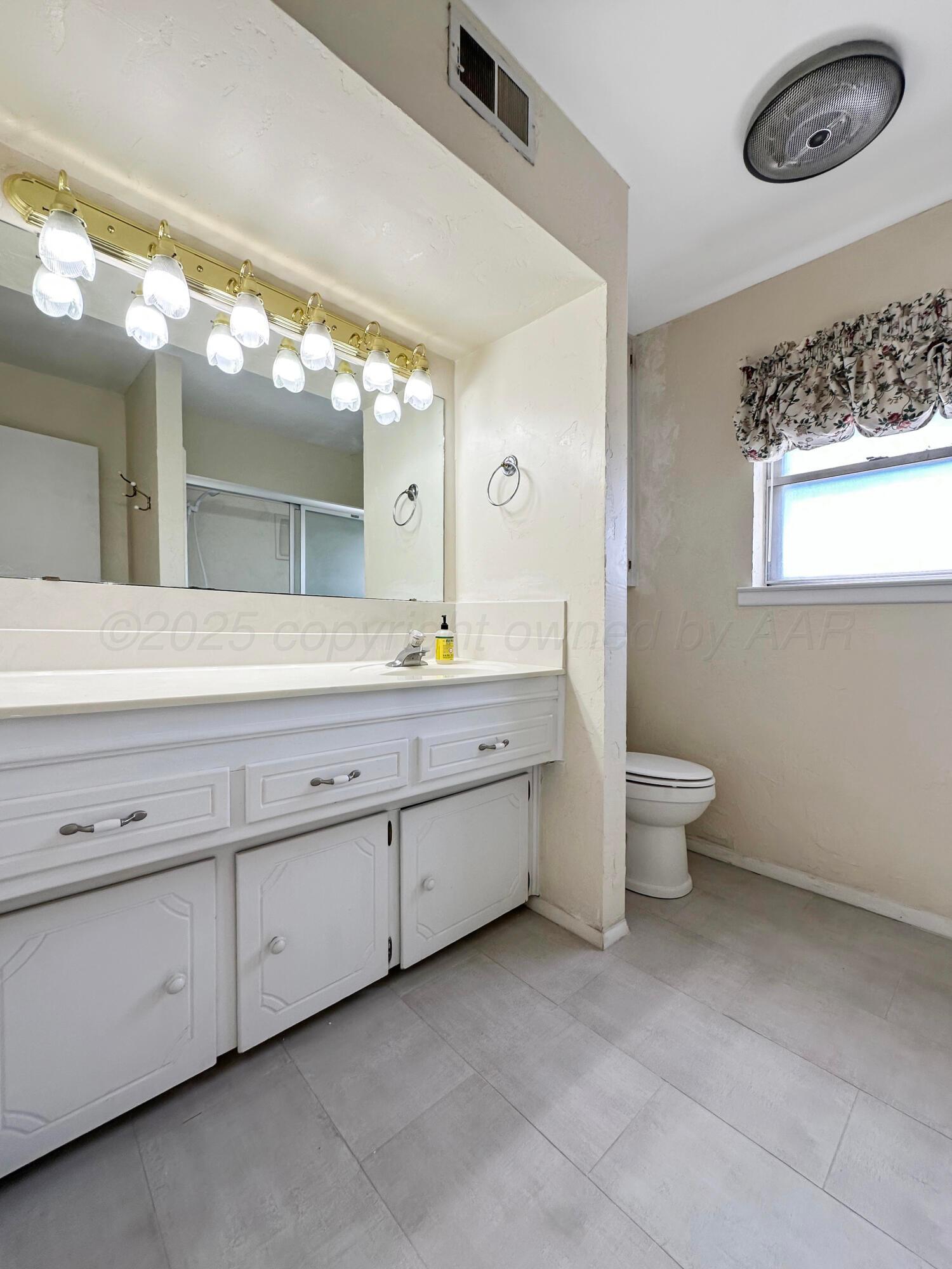 1421 Marigold Street Borger, TX 79007 - Photo 11 of 26 a bathroom with a double vanity sink a toilet and a mirror