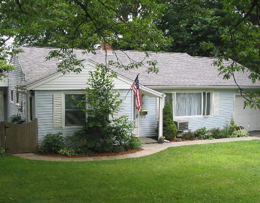 a view of a house with brick walls and a yard with plants