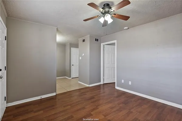 an empty room with wooden floor and ceiling fan
