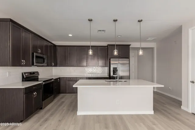 a kitchen with stainless steel appliances granite countertop a sink a stove a refrigerator and cabinets