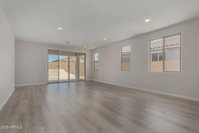 a view of an empty room with wooden floor and windows