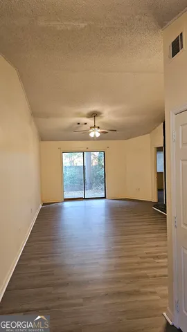 a view of empty room with wooden floor and fan