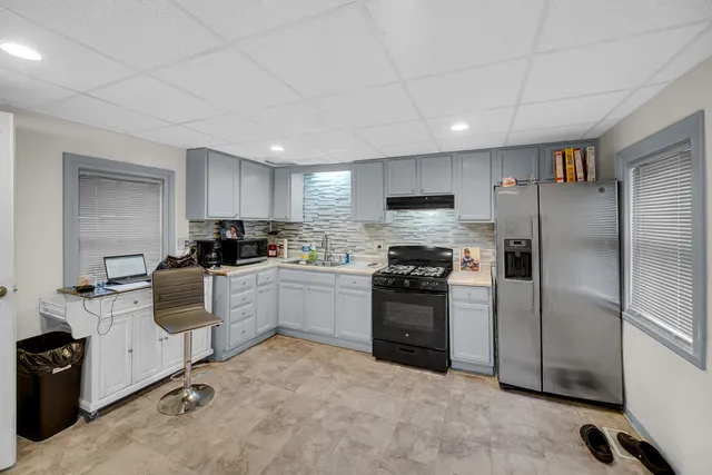 a kitchen with a refrigerator a sink a stove top oven a cabinetry and kitchen island