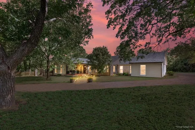 a view of a yard in front of a house with large trees