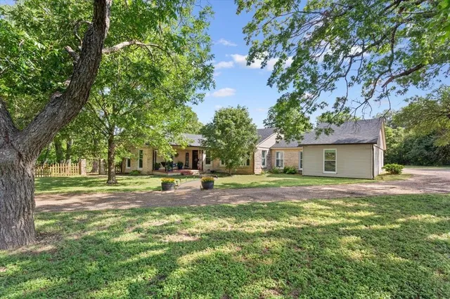 a view of a house with a yard and large trees