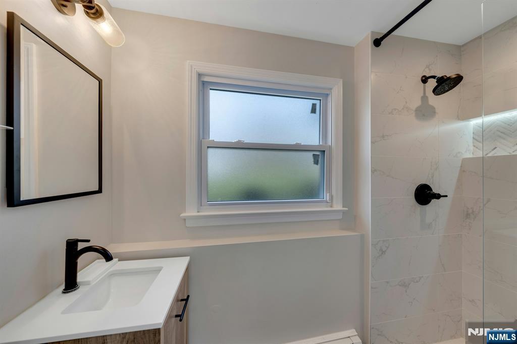 108 Hendrickson Street Haworth, NJ 07641 - Photo 26 of 38 a bathroom with a sink a mirror and window