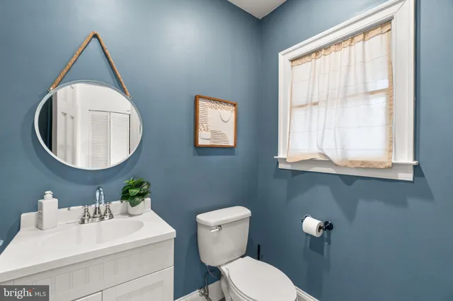 a bathroom with a granite countertop sink toilet and mirror