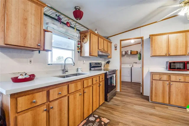 a kitchen with stainless steel appliances a sink dishwasher and cabinets with wooden floor