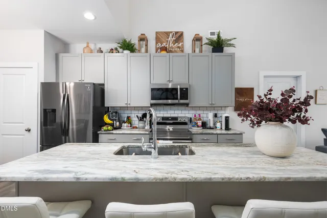 a kitchen with stainless steel appliances granite countertop a refrigerator a stove a microwave and dining table