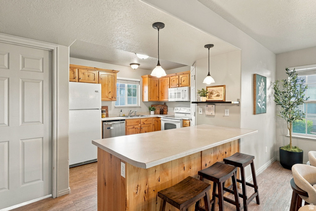1041 South 1850th Street West Springville, UT 84663 - Photo 11 of 35 Kitchen featuring wood cabinetry, white appliances, and a central island with countertop seating