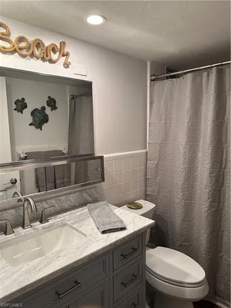 a bathroom with a granite countertop sink a toilet and a shower