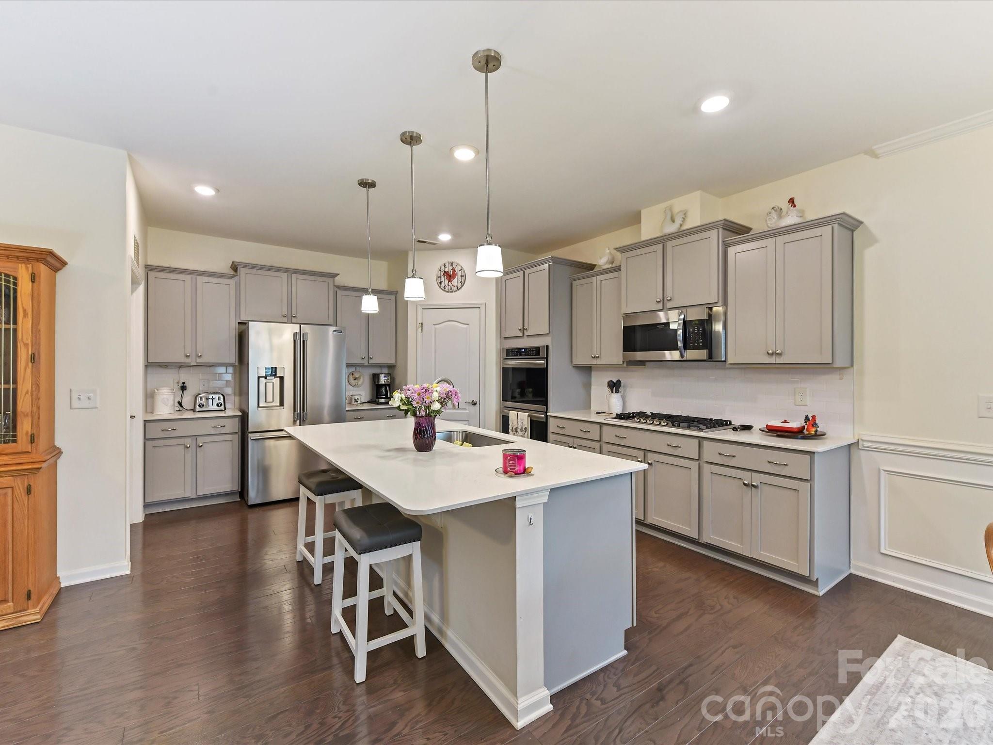 3302 Oliver Stanley Trail Lancaster, SC 29720 - Photo 10 of 48 a kitchen with stainless steel appliances kitchen island granite countertop a sink a stove a refrigerator and white cabinets with wooden floor