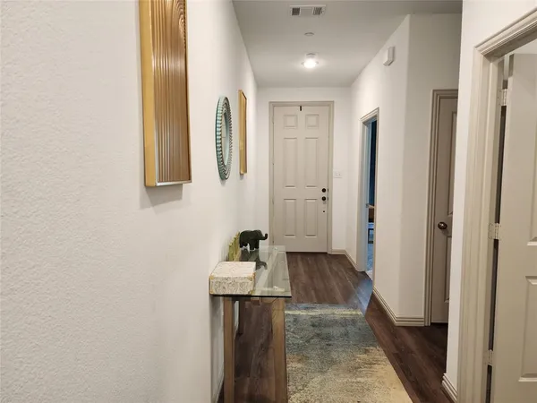 a view of a hallway with wooden floor and a bathroom