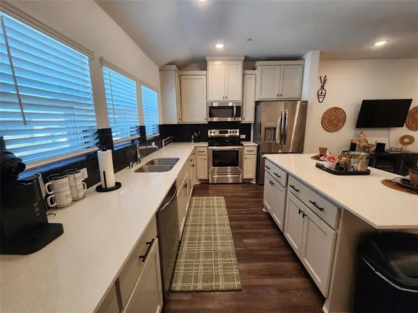 a kitchen with white cabinets a sink and appliances