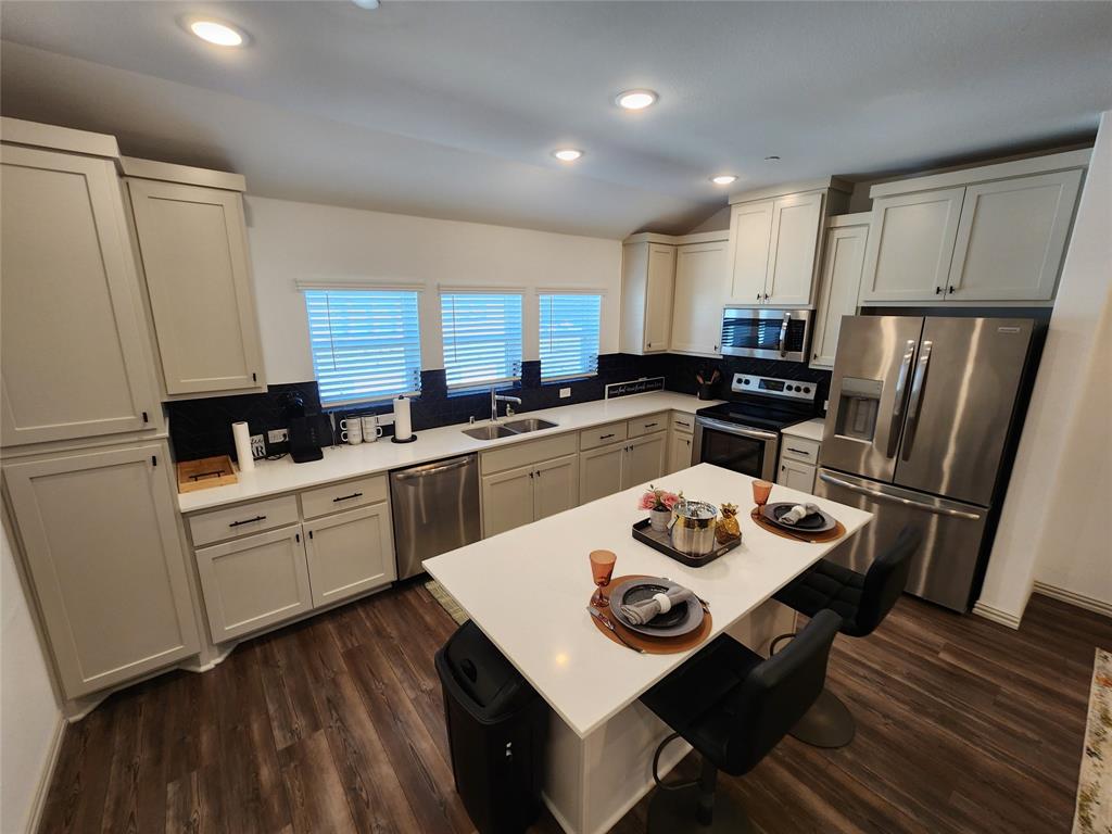 4704 Haltom Road Haltom City, TX 76117 - Photo 6 of 28 a kitchen with a refrigerator a stove a sink dishwasher a dining table and chairs with wooden floor