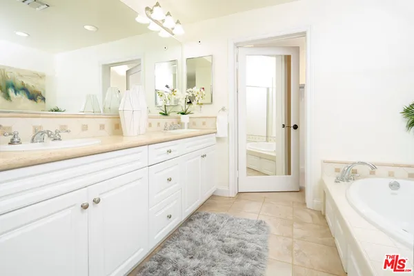 a spacious bathroom with a tub sink and mirror