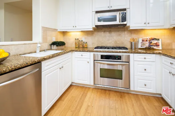 a kitchen with granite countertop white cabinets and white appliances