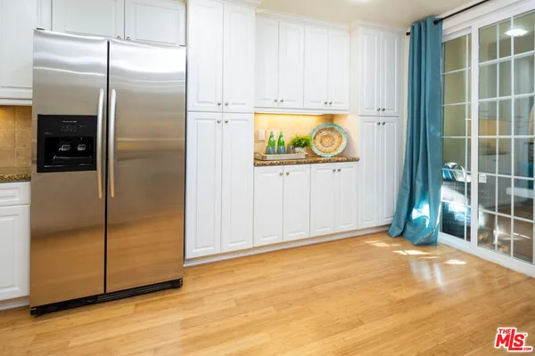 a view of an empty room with wooden floor and a kitchen