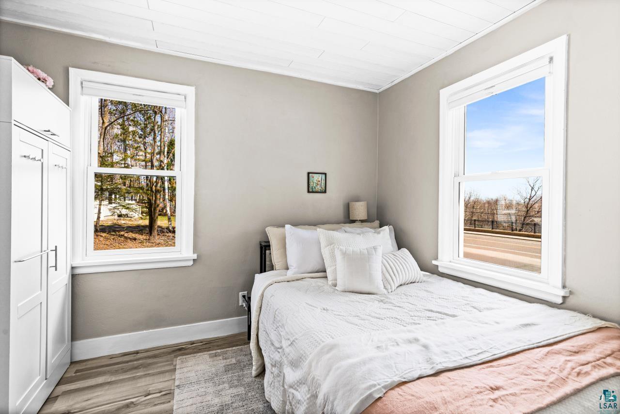 3645 Haines Road Hermantown, MN 55811 - Photo 21 of 35 Room featuring wood-finish flooring, two large windows with white trim, and light gray painted walls