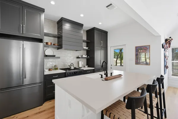 a kitchen with a refrigerator a stove a sink and chairs