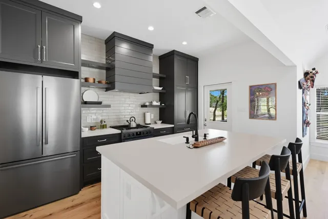 a kitchen with a refrigerator a stove a sink and chairs