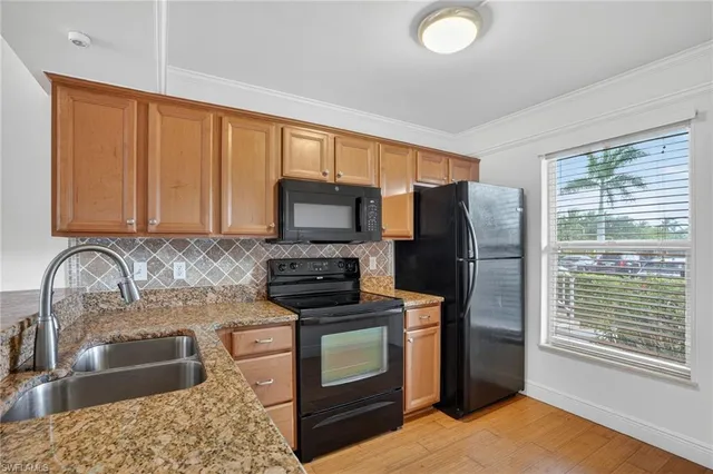 a kitchen with granite countertop a stove a sink and a refrigerator