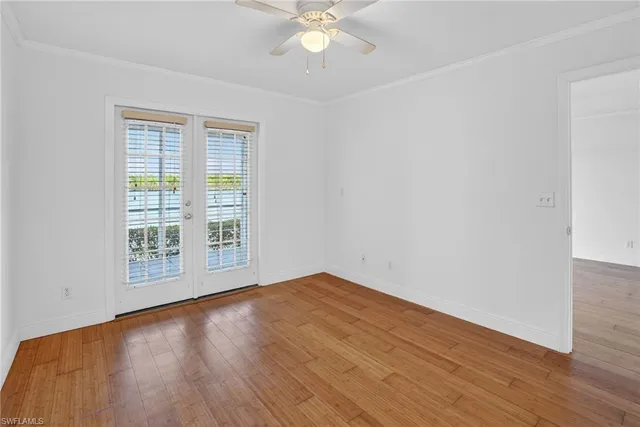 an empty room with wooden floor chandelier fan and windows