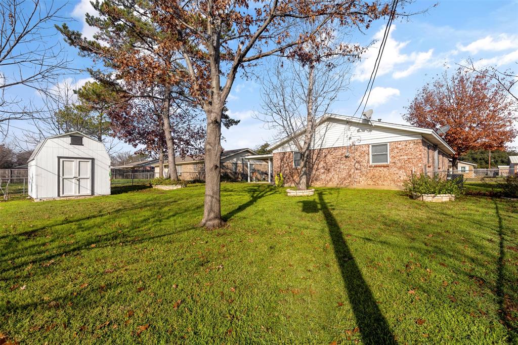 708 East Prairie View Road Crowley, TX 76036 - Photo 18 of 21 Spacious green lawn with a white storage shed and mature trees