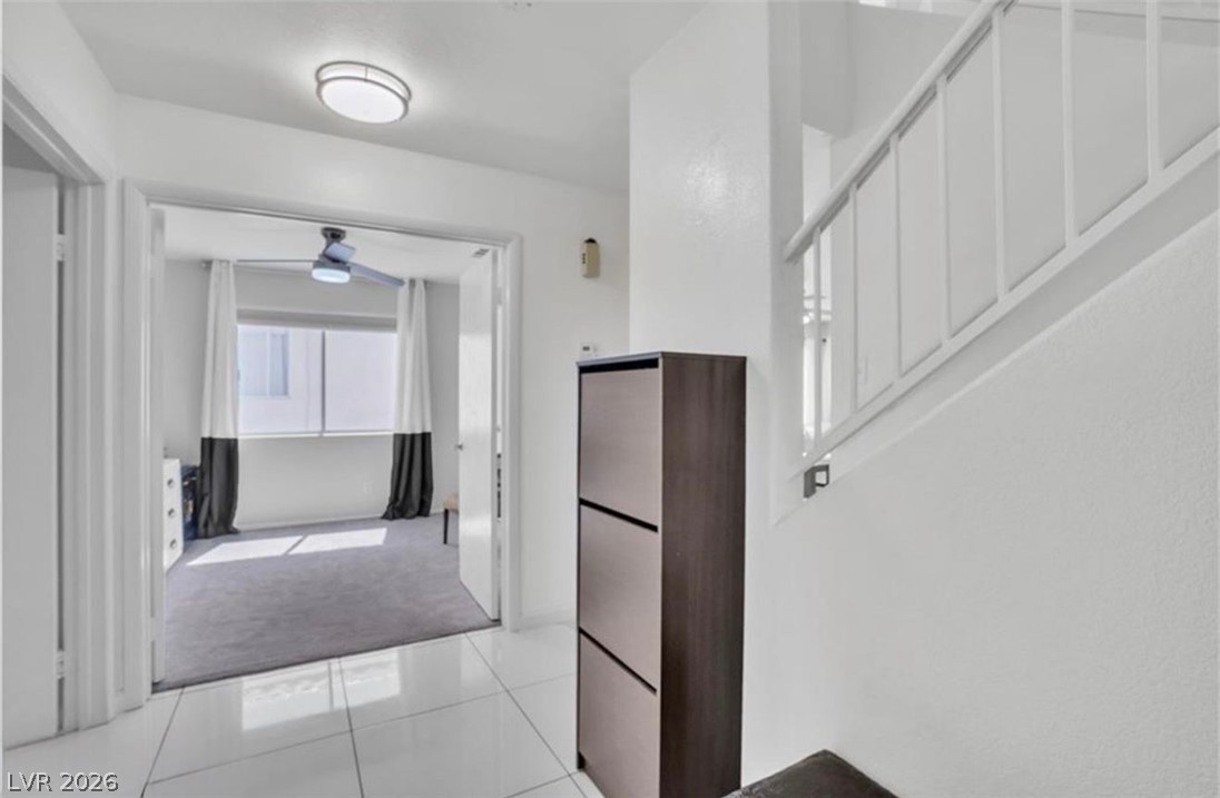 6429 Winding Ridge Las Vegas, NV 89156 - Photo 17 of 22 A well-lit entry hall with tile flooring leads to an inviting carpeted room, featuring an overhead ceiling fan.