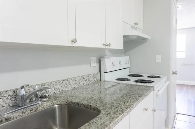 a kitchen with granite countertop a sink and a stove