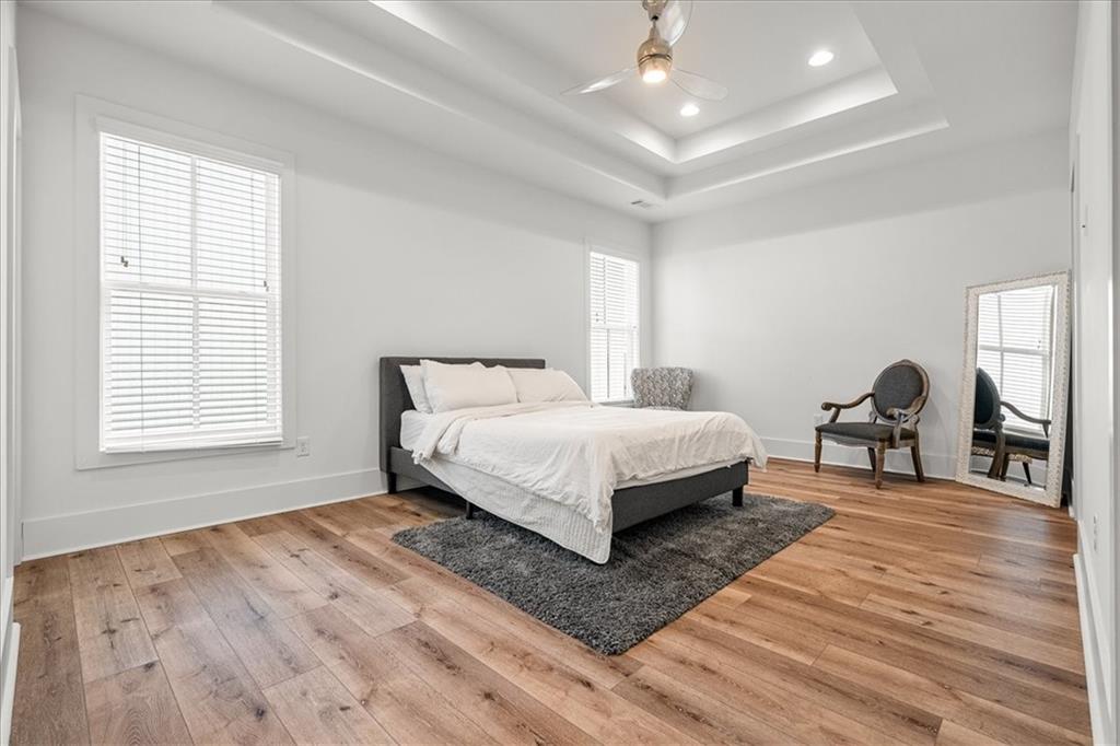 5862 Westin Road Atlanta, GA 30328 - Photo 19 of 43 a bedroom with a bed a dresser and wooden floor
