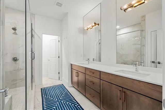 a bathroom with a double vanity sink a large mirror and a shower