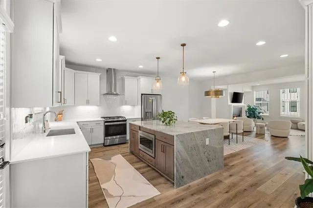 an open kitchen with kitchen island wooden floors and stainless steel appliances
