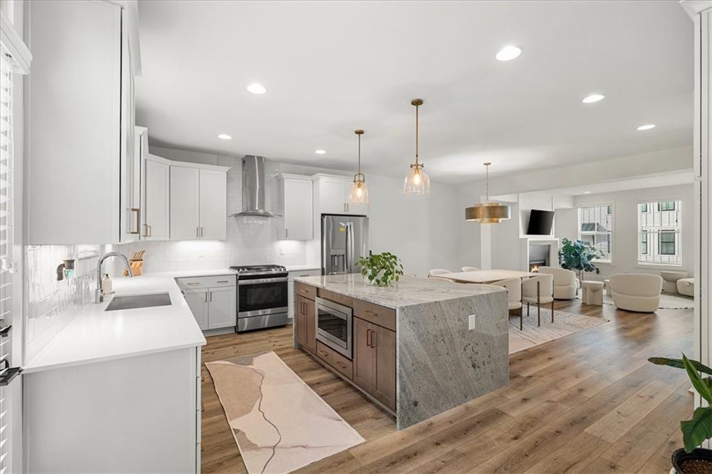 5862 Westin Road Atlanta, GA 30328 - Photo 9 of 43 an open kitchen with kitchen island wooden floors and stainless steel appliances