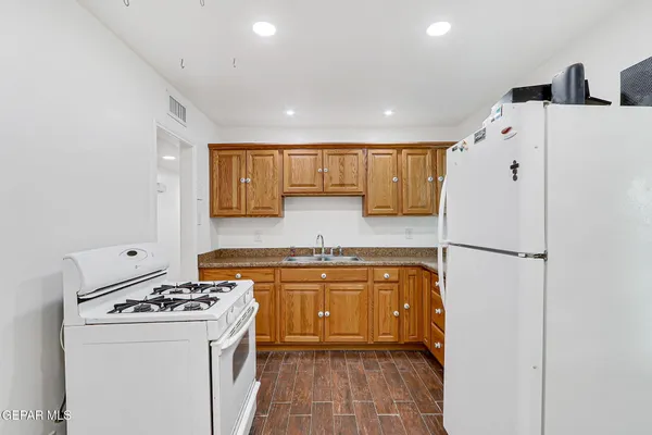 a kitchen with stainless steel appliances granite countertop a refrigerator a stove and a sink with wooden floors