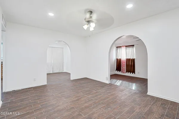 an empty room with wooden floor chandelier and windows