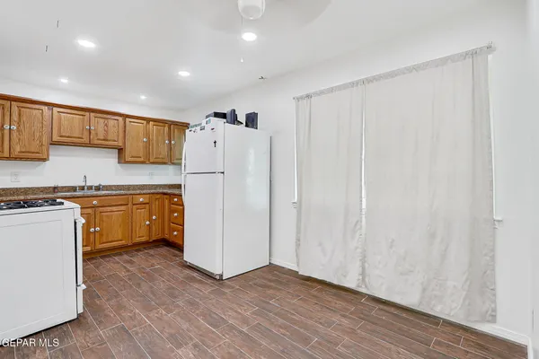 a kitchen with granite countertop a refrigerator a sink and white cabinets