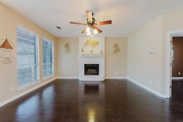 a view of a livingroom with a fireplace a ceiling fan and wooden floor