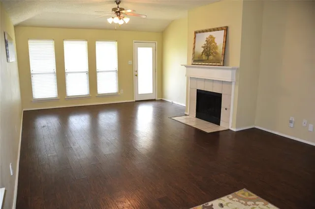 a view of a livingroom with wooden floor a fireplace and windows