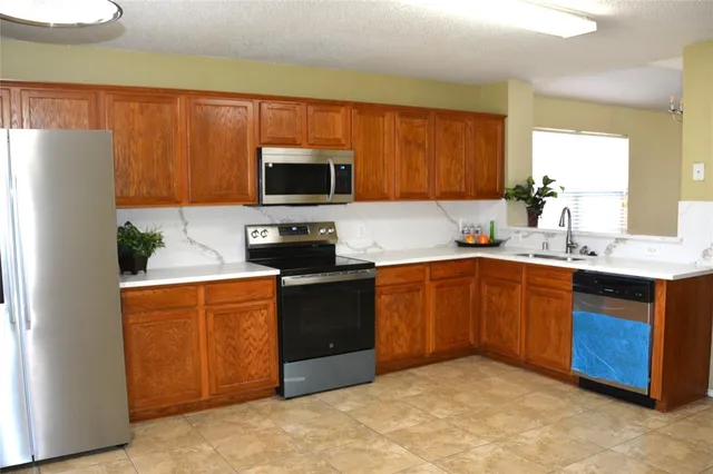 a kitchen with stainless steel appliances granite countertop a stove a sink dishwasher a refrigerator and a microwave oven