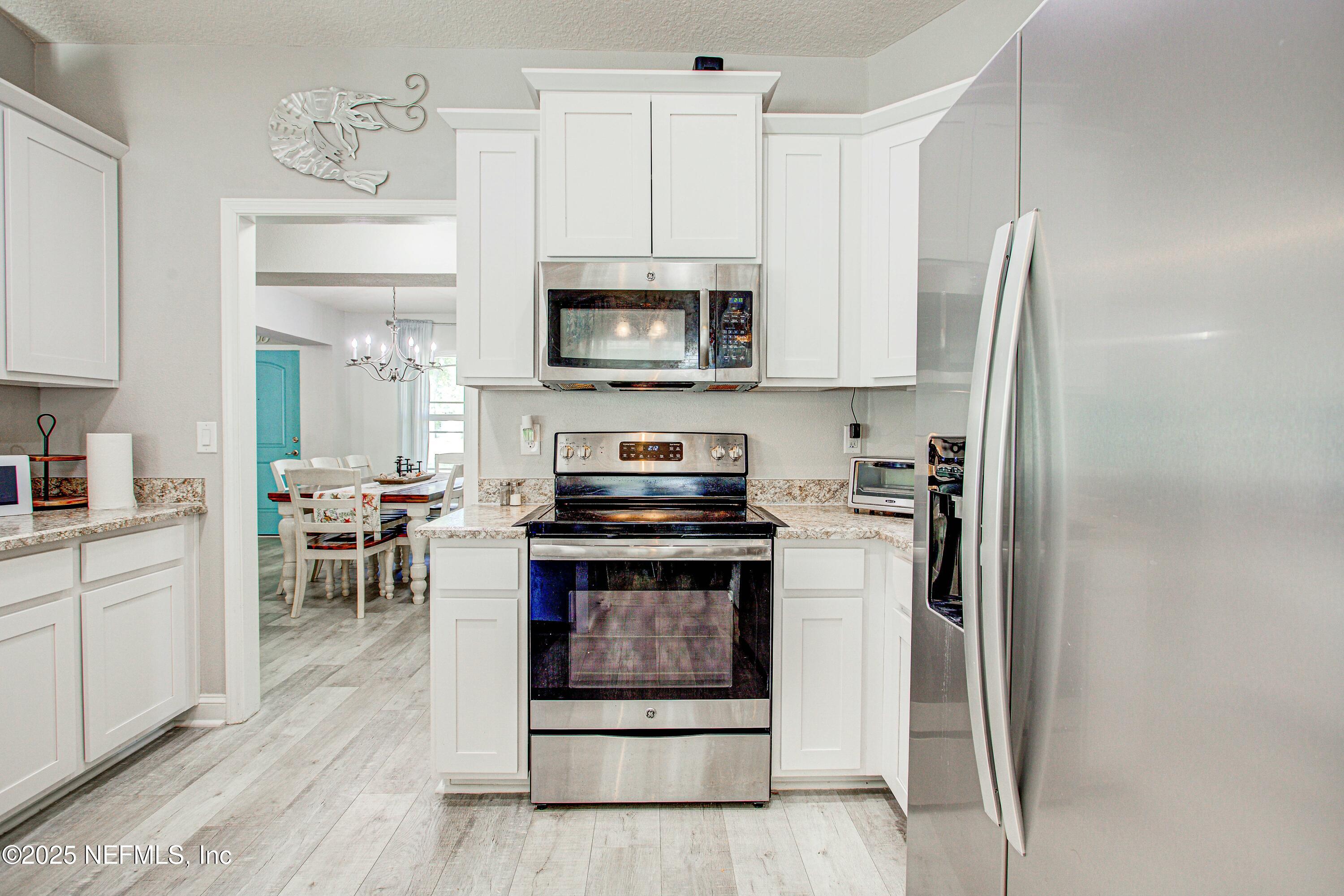 88083 Maybourne Road Yulee, FL 32097 - Photo 46 of 76 a kitchen with stainless steel appliances granite countertop a stove a refrigerator and a microwave