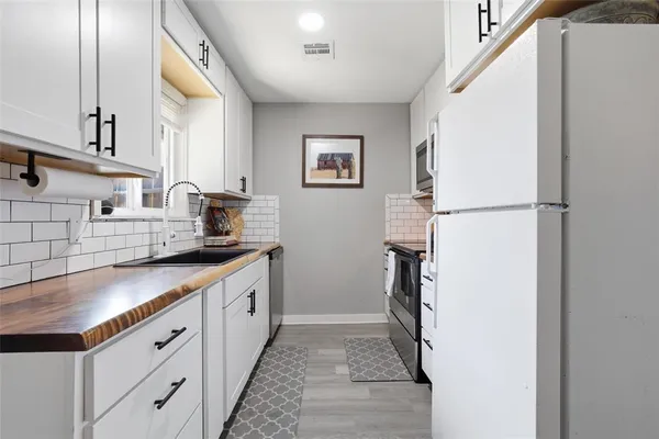 a kitchen with stainless steel appliances a refrigerator sink and white cabinets