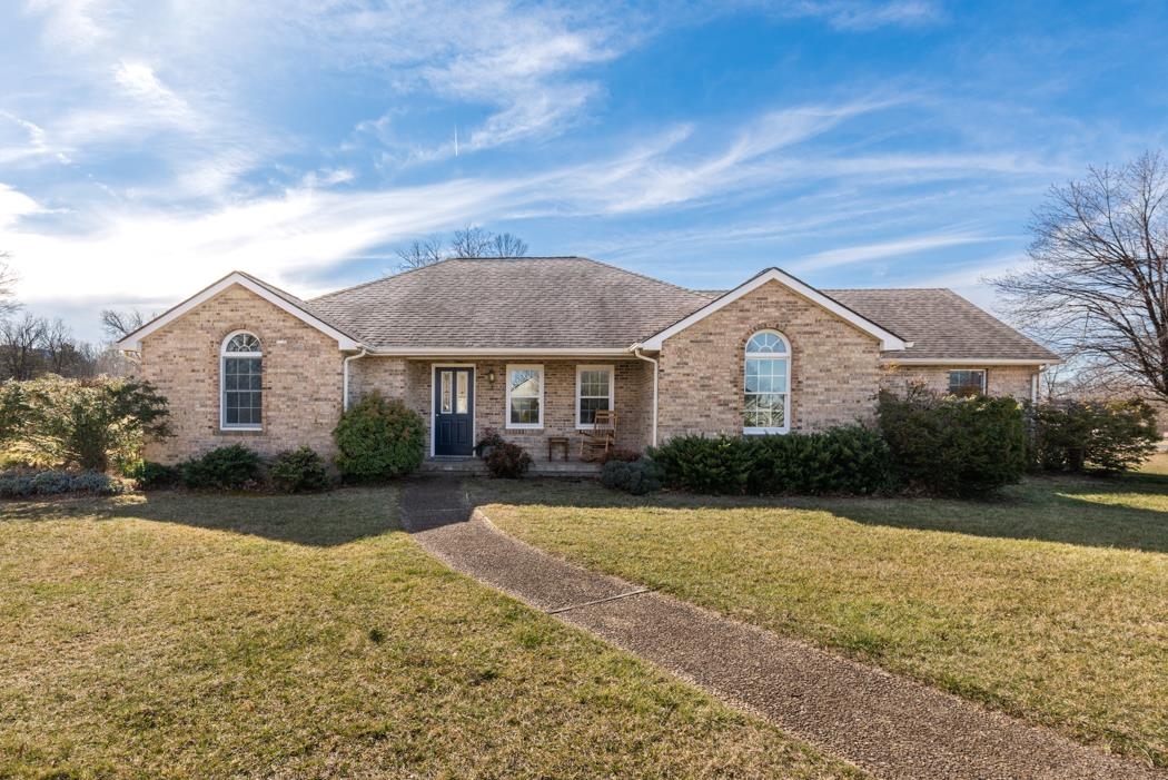 a view of a white house next to a yard with a big trees