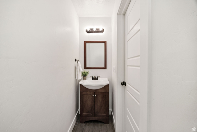 1552 Sumac Drive Logan, UT 84321 - Photo 48 of 72 Powder room featuring a dark wood-finish vanity with a white ceramic basin sink, a wood-framed mirror, and a three-light vanity fixture