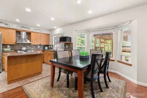 a kitchen with stainless steel appliances granite countertop a stove a refrigerator a sink dishwasher a dining table and chairs with wooden floor