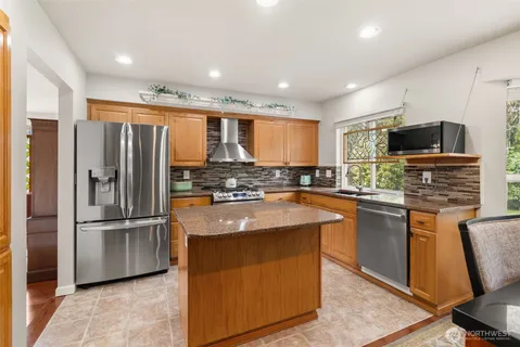 a kitchen with stainless steel appliances granite countertop a refrigerator and a stove top oven